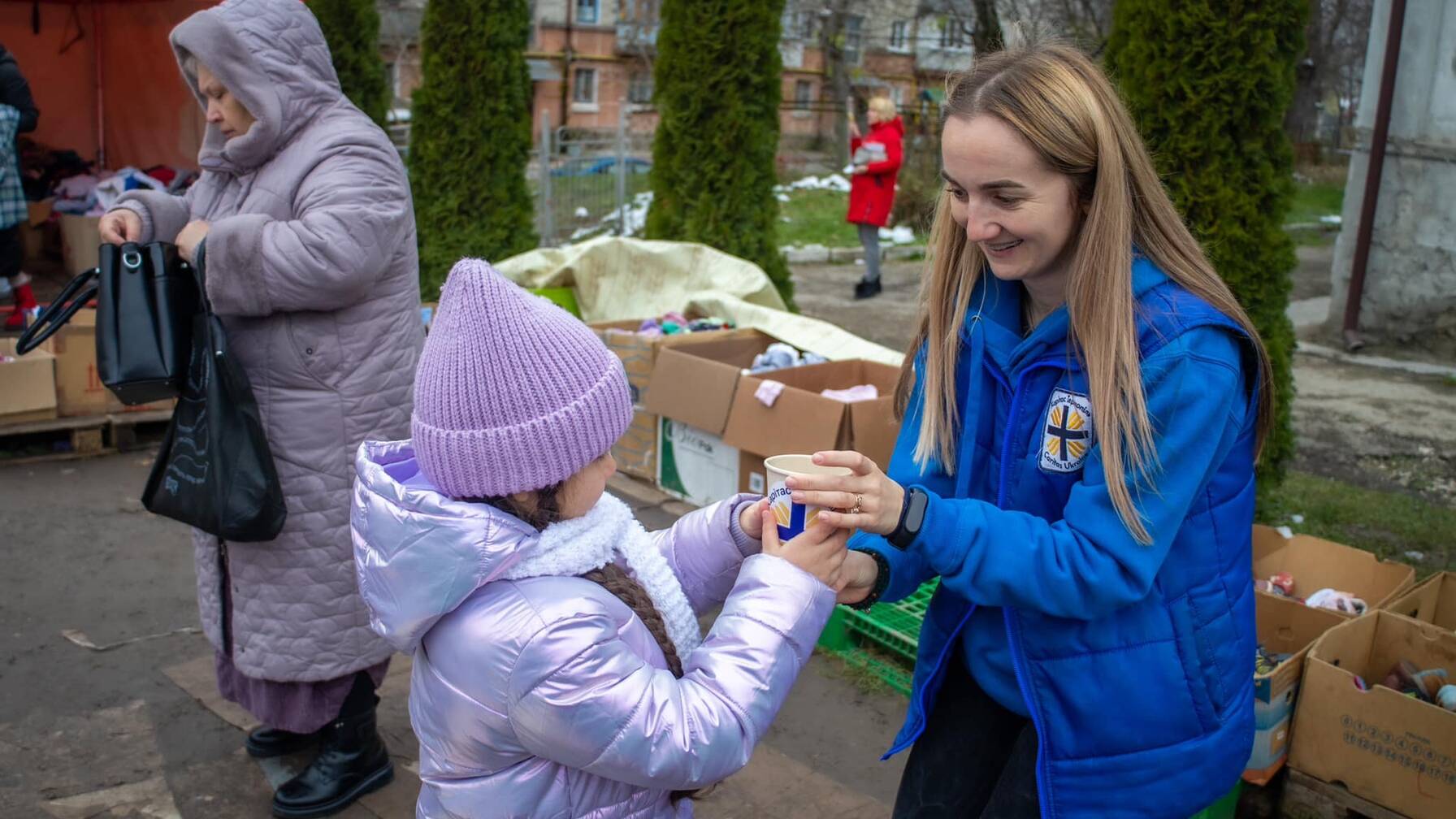 Un piccolo gesto può fare tanto: una volontaria serve del tè caldo e regala un sorriso a una bambina.
