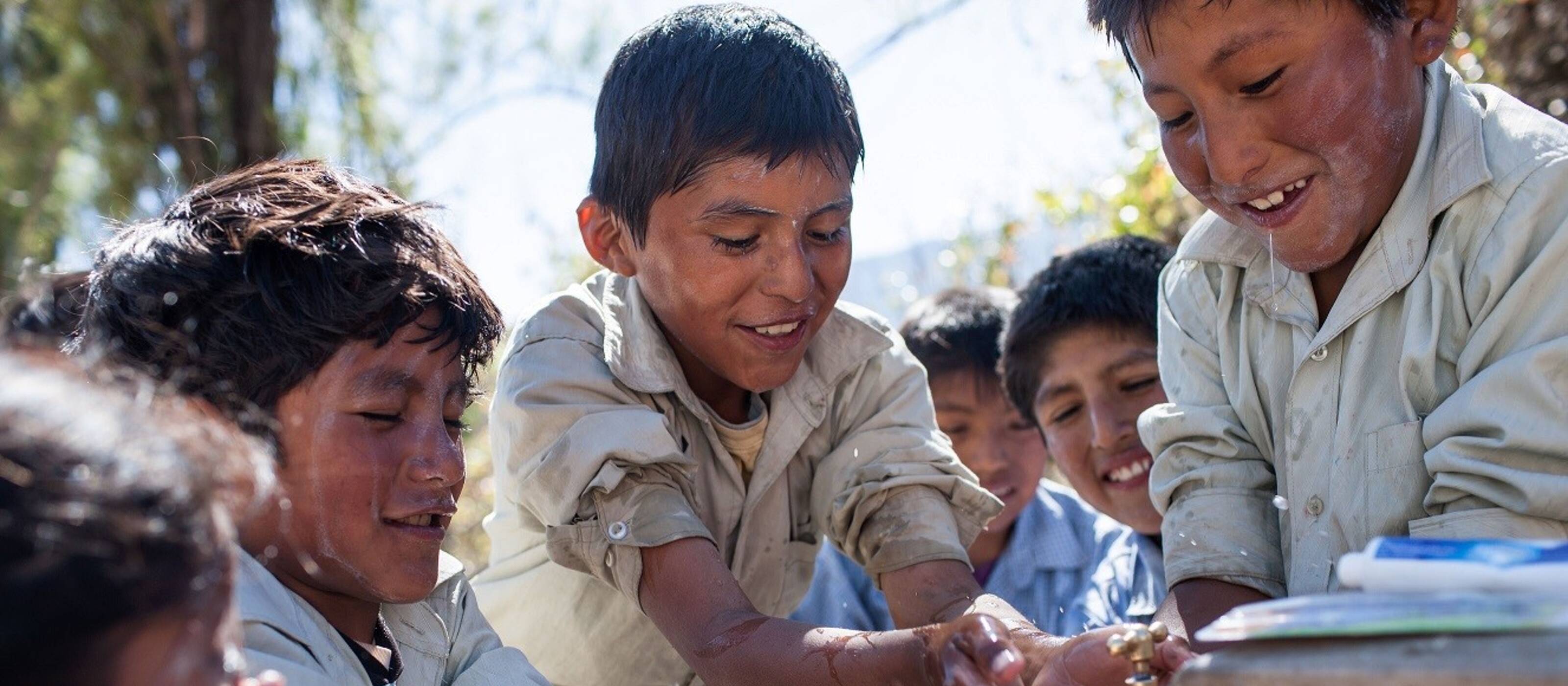Children in Bolivia wash themselves at a well