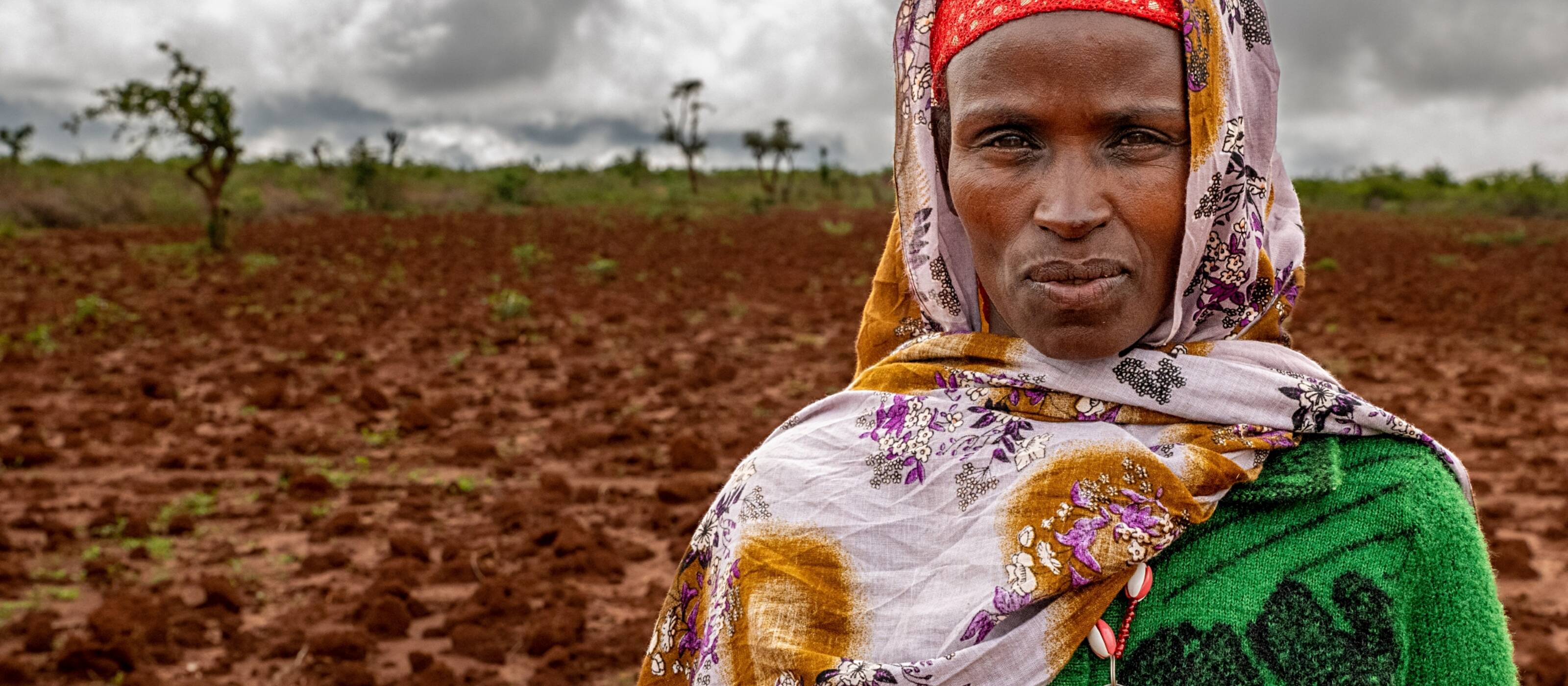 The small farmer Ensane from Ethiopia looks straight into the camera. The field behind her has dried up in the severe drought. 
