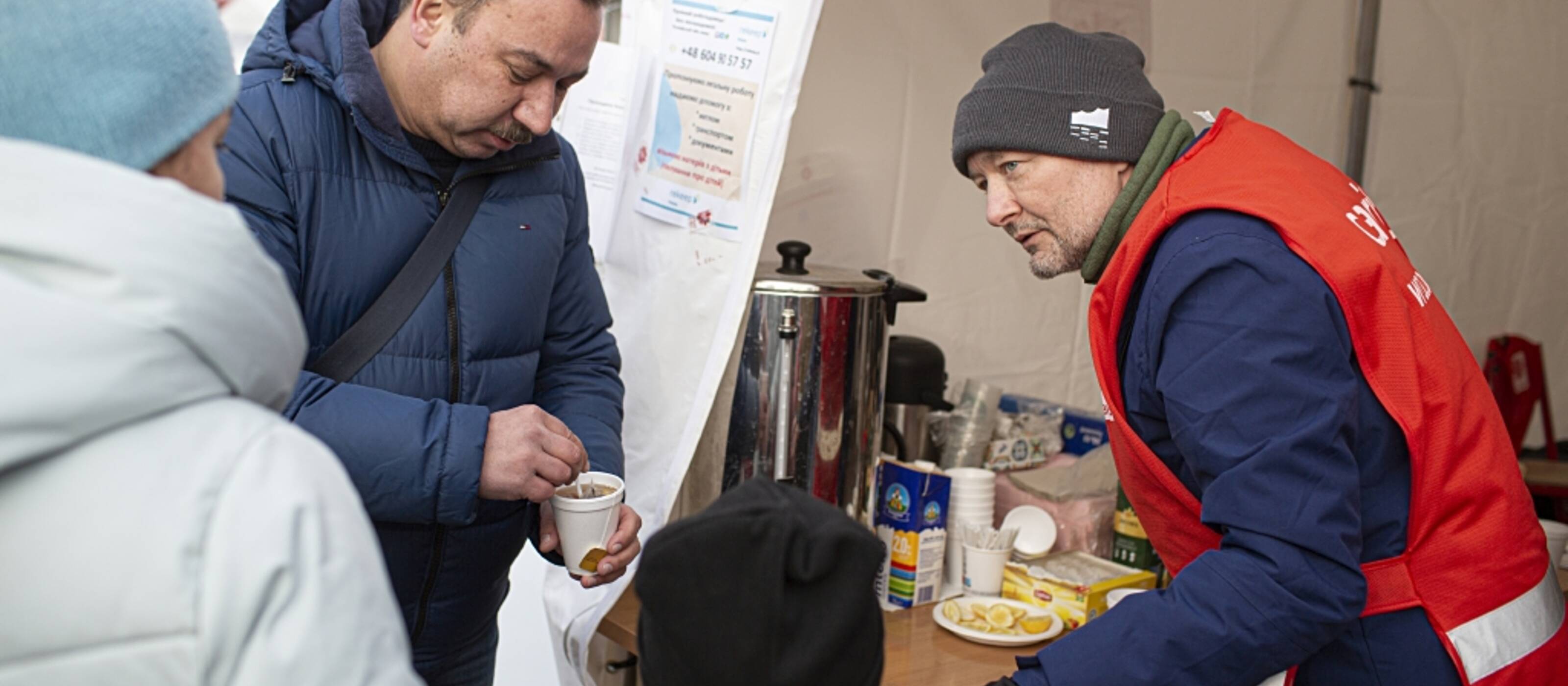 Un operatore della Caritas in Polonia distribuisce bevande calde ai rifugiati provenienti dall'Ucraina.