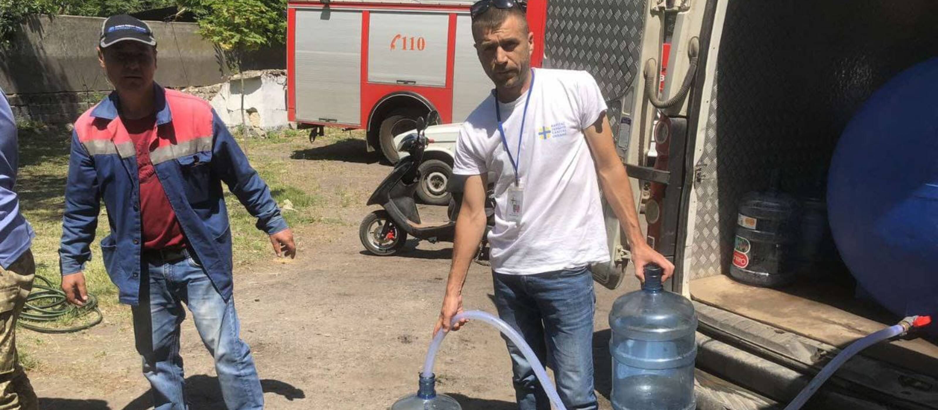 Des collaborateurs de Caritas distribuent de l'eau potable.