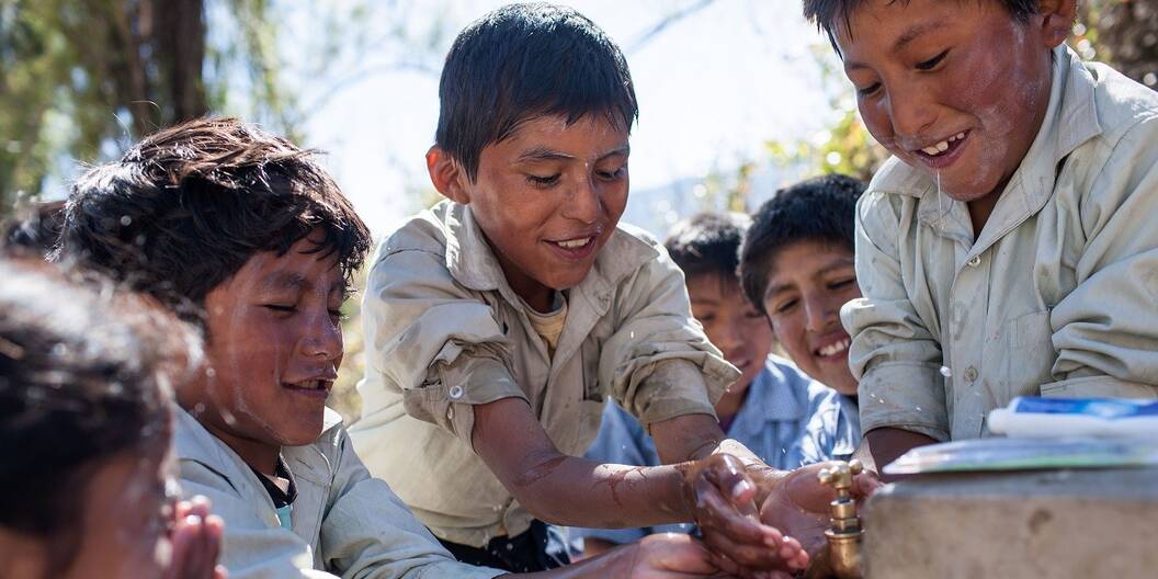 Kinder in Bolivien waschen sich an einem Brunnen